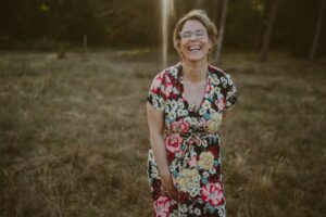 Authentisches Porträt einer lachenden Frau auf einer Sommerwiese – persönlich, humorvoll, lebensnah wie die 53 Fun Facts im Artikel.