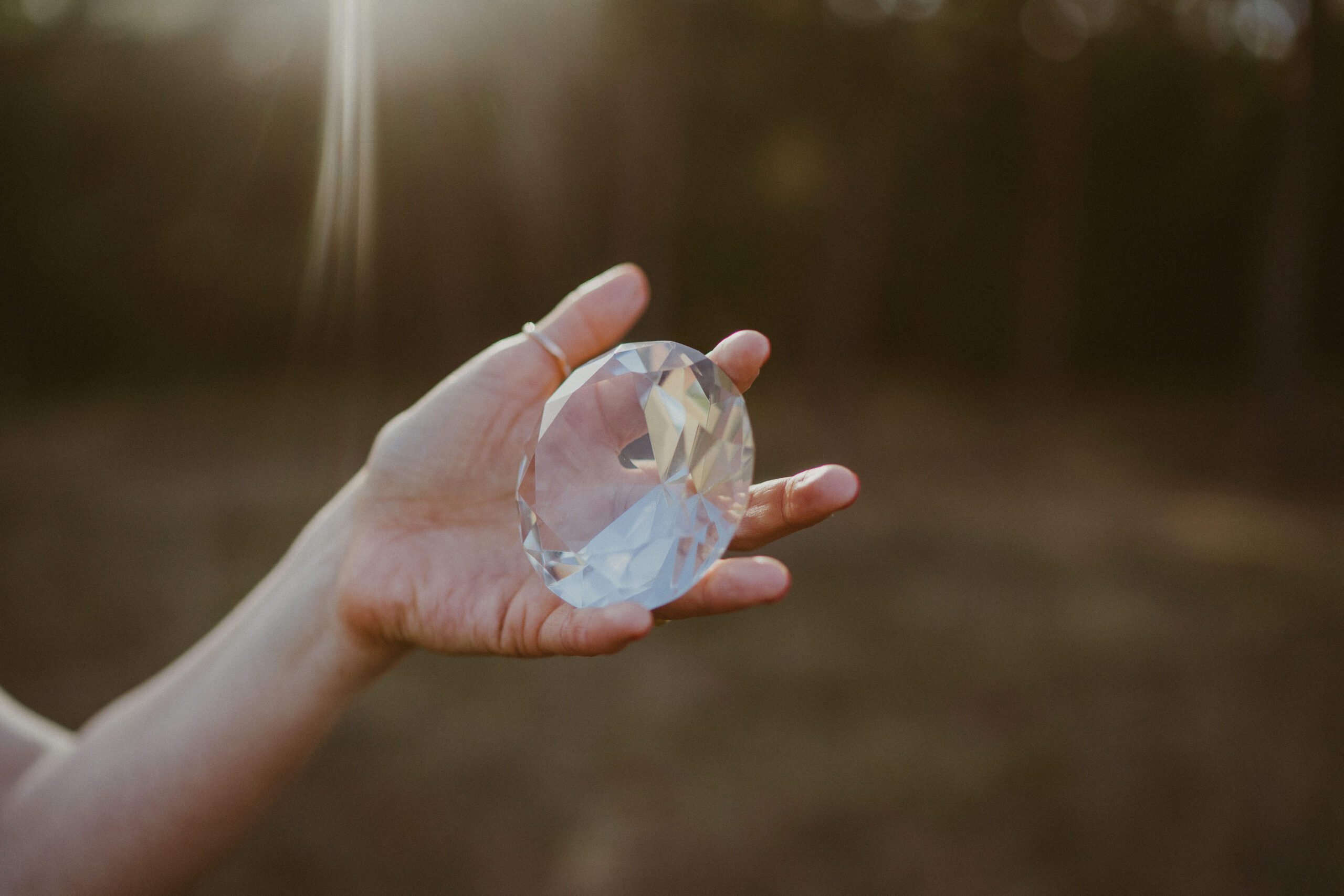 Hand hält einen großen geschliffenen Kristall im Sonnenlicht – Symbol für Klarheit, Facettenreichtum und Strahlkraft einer Marke.