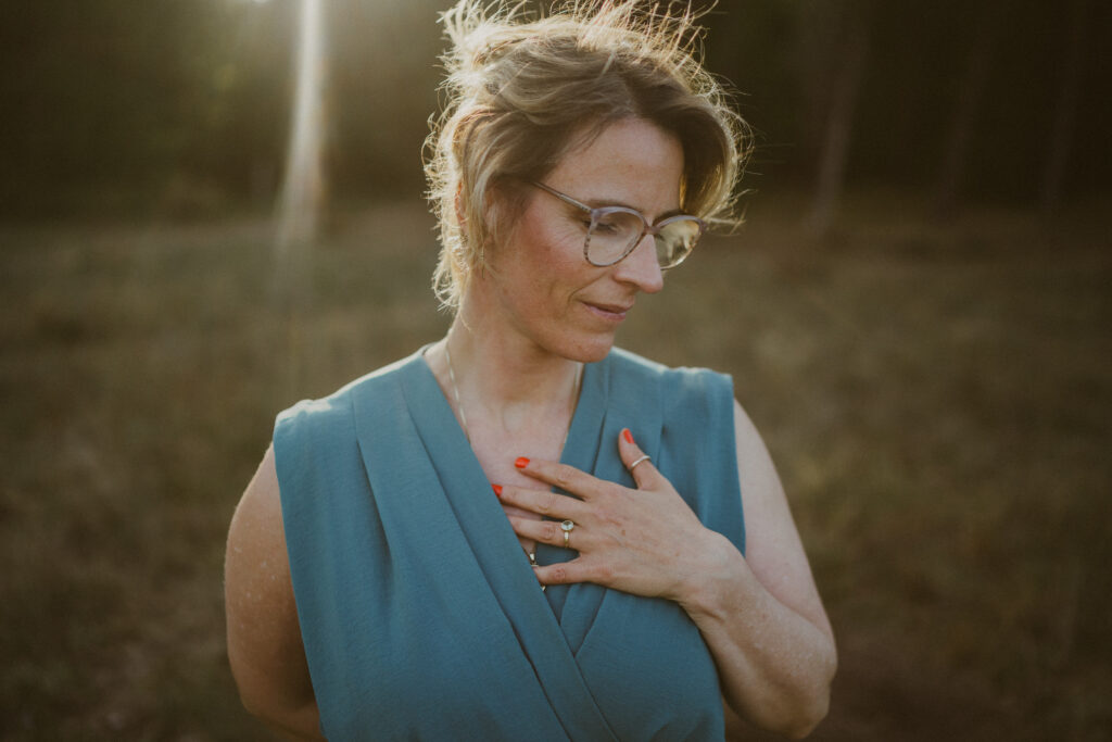 Frau mit geschlossenen Augen und Hand auf dem Herzen – Symbolbild für Verbindung, Achtsamkeit und die Praxis der Ritualarbeit in der Natur