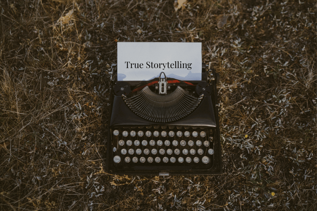Alte Schreibmaschine auf trockenem Gras mit einem eingelegten Blatt Papier, auf dem ‚True Storytelling‘ steht